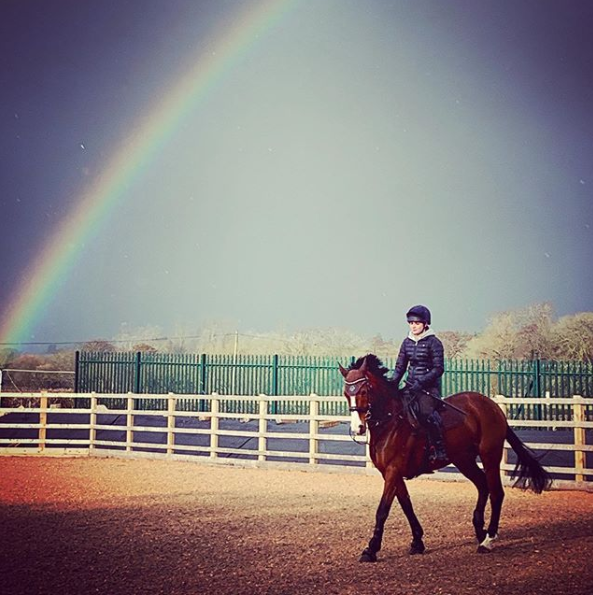 Rider at Unicorn Arena with rainbow behind them